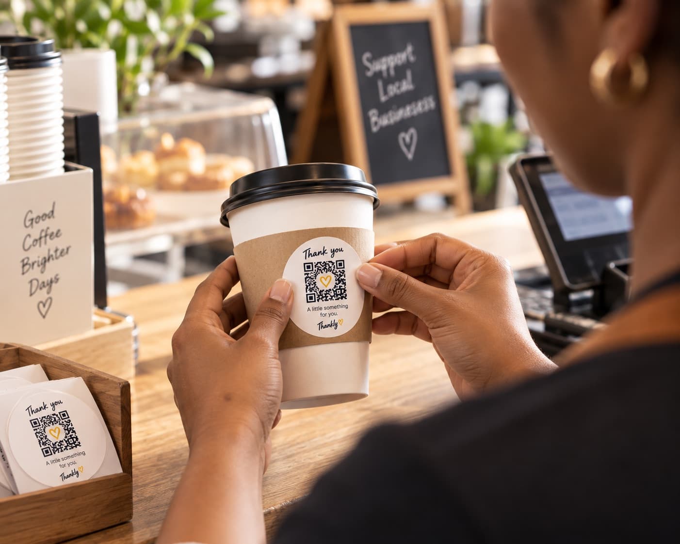 A Thankly QR code being added to a takeaway cup